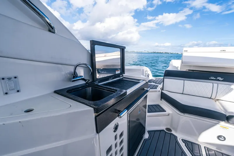 Slide: The Image of 2018 Sea Ray SLX 350 Outboard boat interior with sink and seating, ocean view. - 18