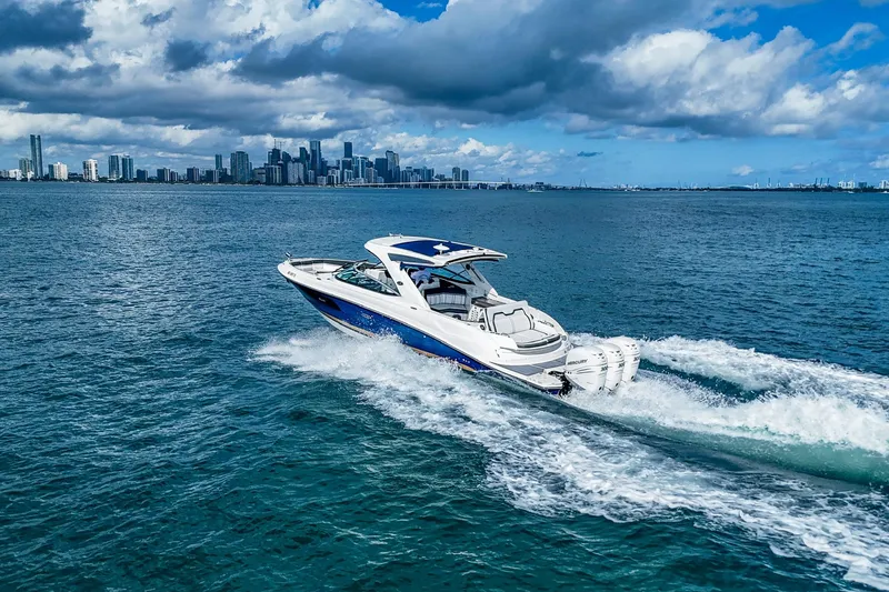 Slide: The Image of 2018 Sea Ray SLX 350 Outboard cruising on blue ocean with city skyline backdrop. - 4