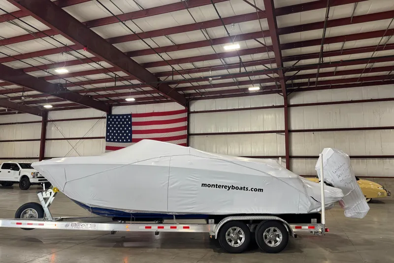 Slide: The Image of 2023 Monterey 255SS Super Sport boat covered in a warehouse with American flag. - 25