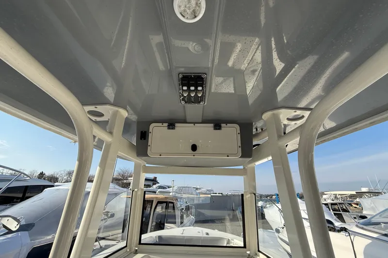 Slide: The Image of 2021 NauticStar 28 XS boat interior view with overhead console and clear sky. - 11