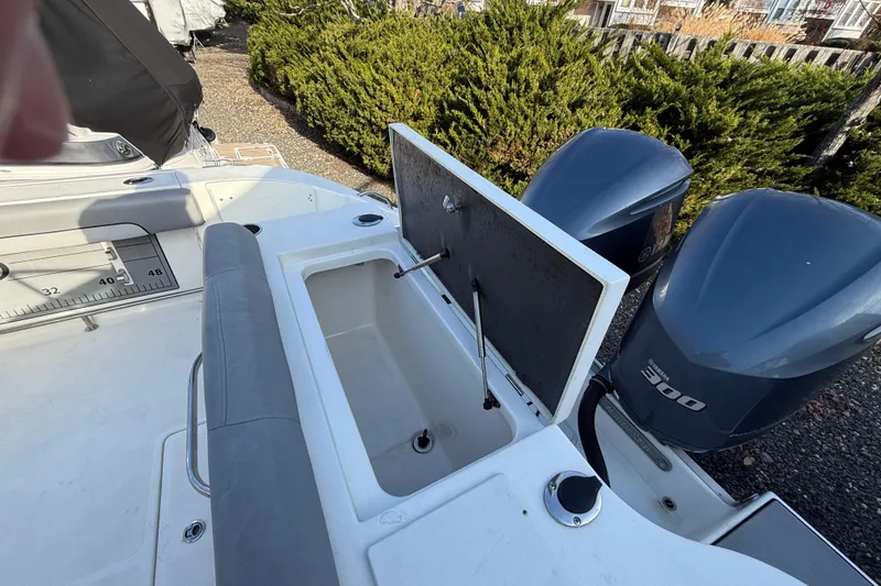 Slide: The Image of 2021 NauticStar 28 XS boat with open storage compartment and dual outboard engines. - 18