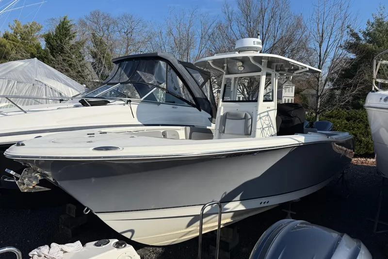 The Image of 2021 NauticStar 28 XS boat in storage, surrounded by trees and other boats. - 2