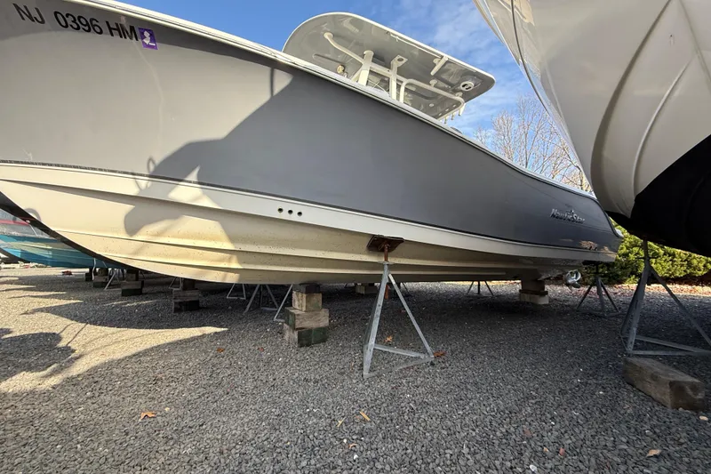 Slide: The Image of 2021 NauticStar 28 XS boat on stands, gravel lot, side view. - 26