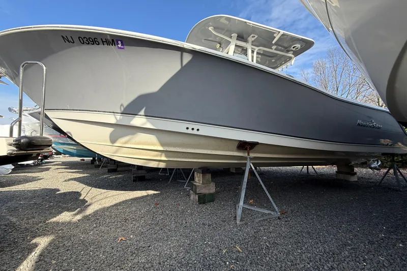 Slide: The Image of 2021 NauticStar 28 XS boat on stands, gravel lot, clear sky background. - 27