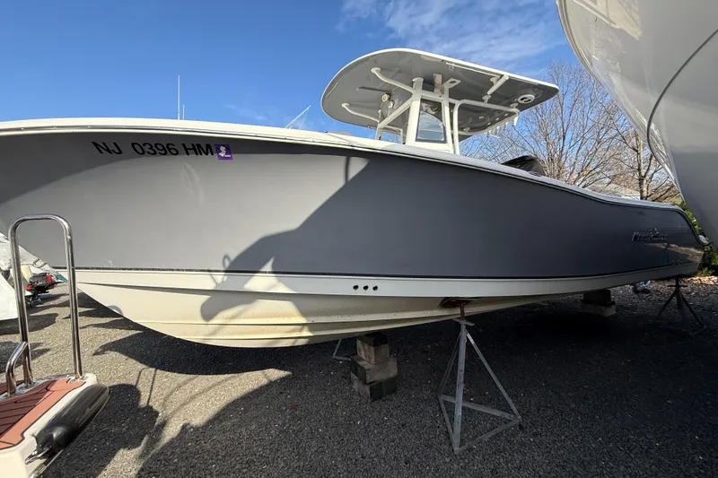 Slide: The Image of 2021 NauticStar 28 XS boat on stands, gray hull, clear sky background. - 28