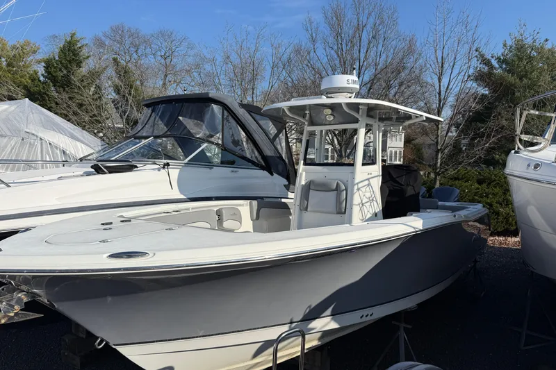 Slide: The Image of 2021 NauticStar 28 XS boat in a marina, surrounded by trees and other boats. - 4