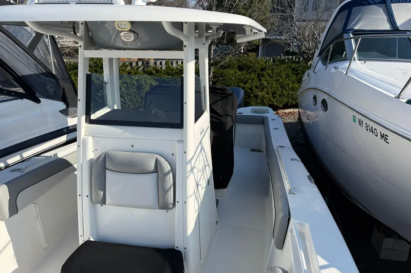 Slide: The Image of 2021 NauticStar 28 XS boat interior with seating and console, docked beside another vessel. - 7