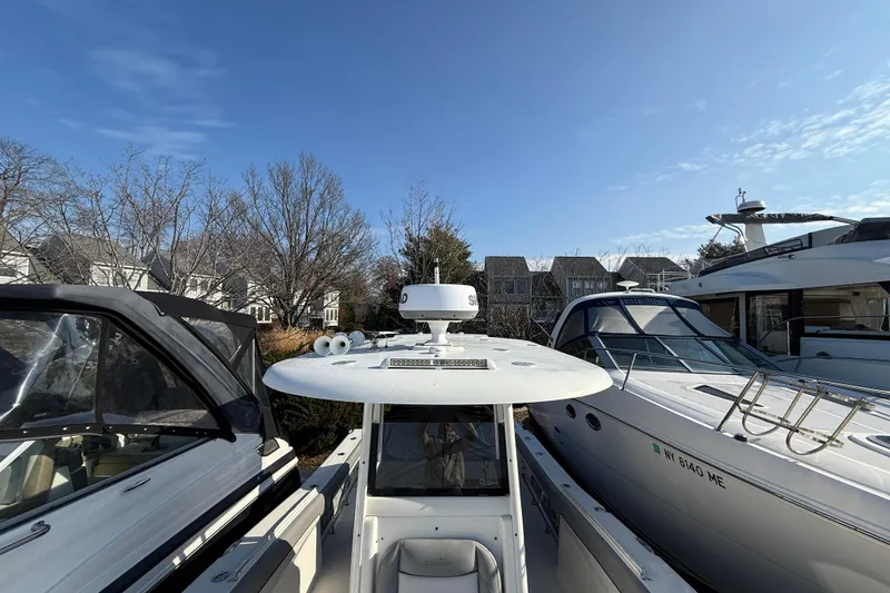 Slide: The Image of 2021 NauticStar 28 XS boat docked between two other boats under a clear blue sky. - 8