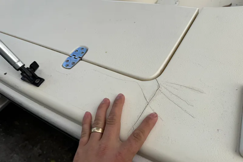 Slide: The Image of Hand inspecting cracks on 2006 Scout 170 Costa boat surface near hinge. - 27