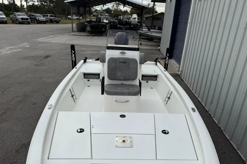 Slide: The Image of 2026 Avid 19 FSX boat with gray seating, parked outdoors near a metal building. - 3