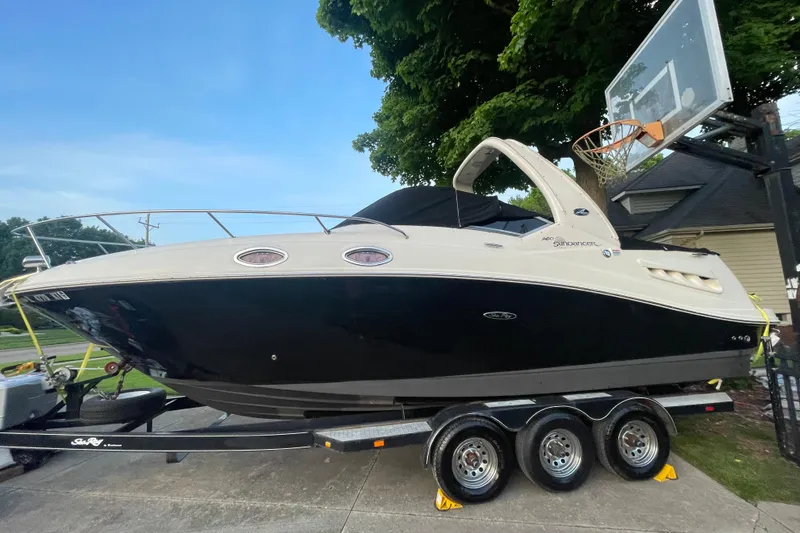 The Image of 2006 Sea Ray 260 Sundancer boat on trailer, parked outdoors near a basketball hoop. - 0