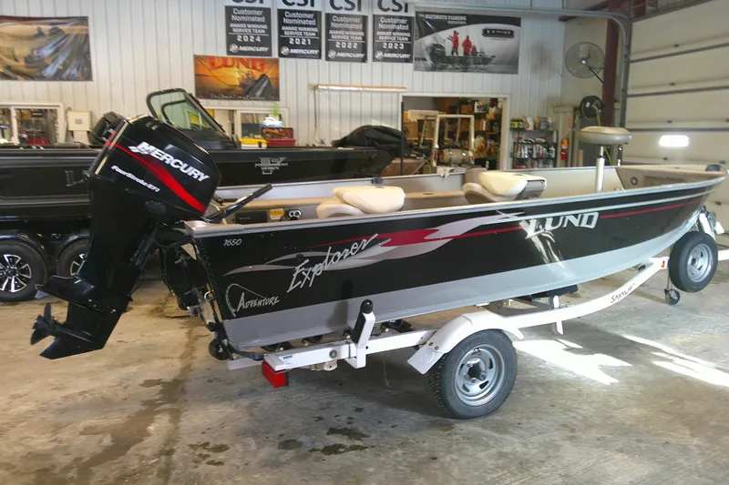 Slide: The Image of 2003 Lund 1650 Explorer Tiller boat with Mercury outboard motor in a showroom. - 2