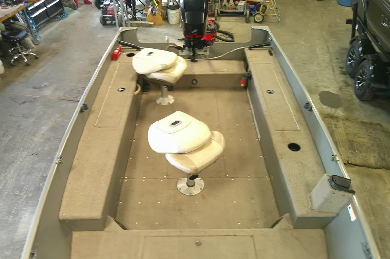 Slide: The Image of 2003 Lund 1650 Explorer Tiller boat interior with two seats in a garage setting. - 5