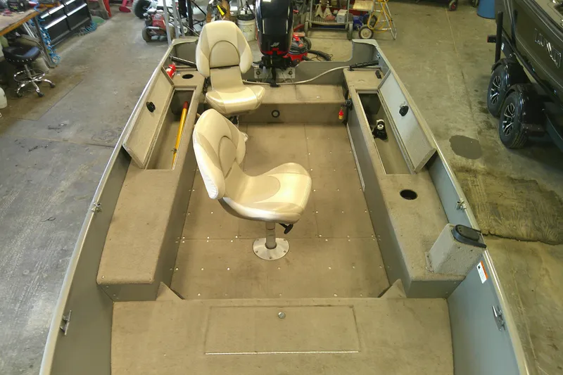 Slide: The Image of 2003 Lund 1650 Explorer Tiller boat interior with two seats in a garage setting. - 6