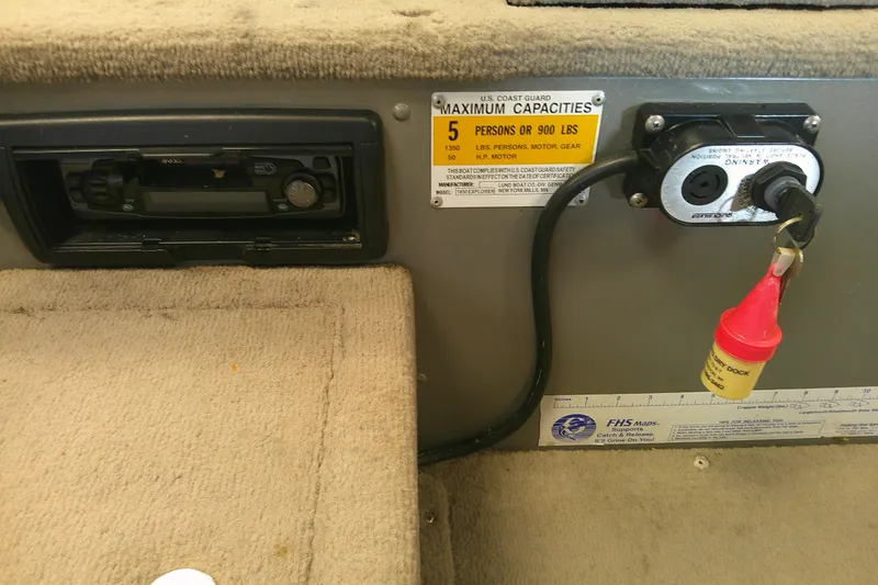 Slide: The Image of 2003 Lund 1650 Explorer Tiller boat interior with capacity label and ignition switch. - 8