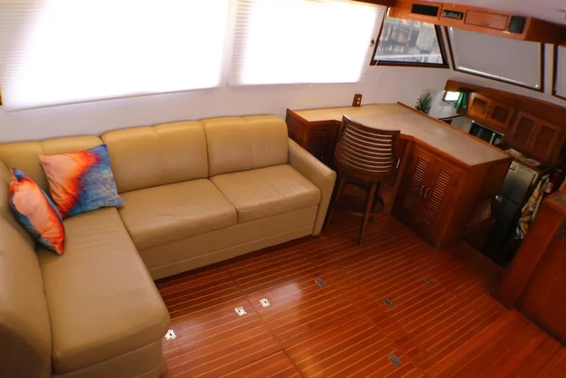 Slide: The Image of 1988 Sea Ranger 46 Sundeck Trawler interior with beige sofa, colorful pillows, and wooden cabinetry. - 20