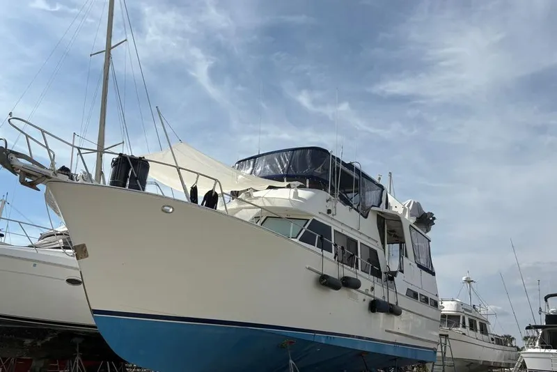 Slide: The Image of 1988 Sea Ranger 46 Sundeck Trawler on land, showcasing its sleek design under a clear sky. - 4