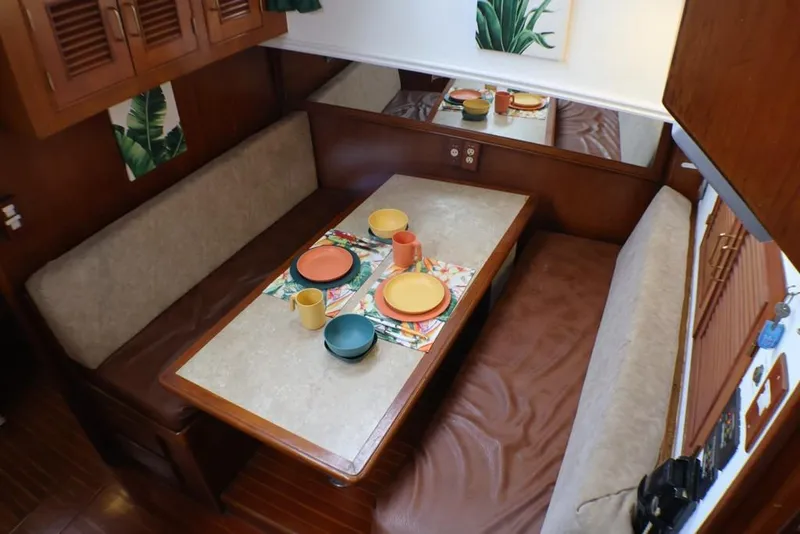 Slide: The Image of 1988 Sea Ranger 46 Sundeck Trawler interior dining area with colorful tableware and cozy seating. - 5