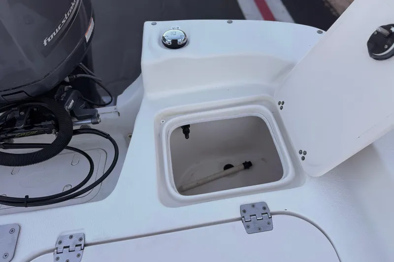 Slide: The Image of 2013 Carolina Skiff 218 boat with open storage compartment and visible engine components. - 20
