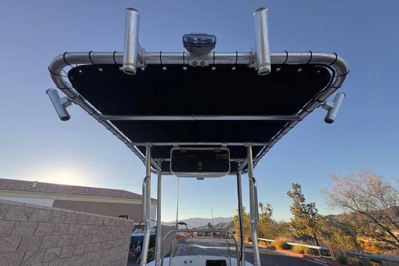 Slide: The Image of 2013 Carolina Skiff 218 boat with T-top and rod holders, under clear blue sky. - 24