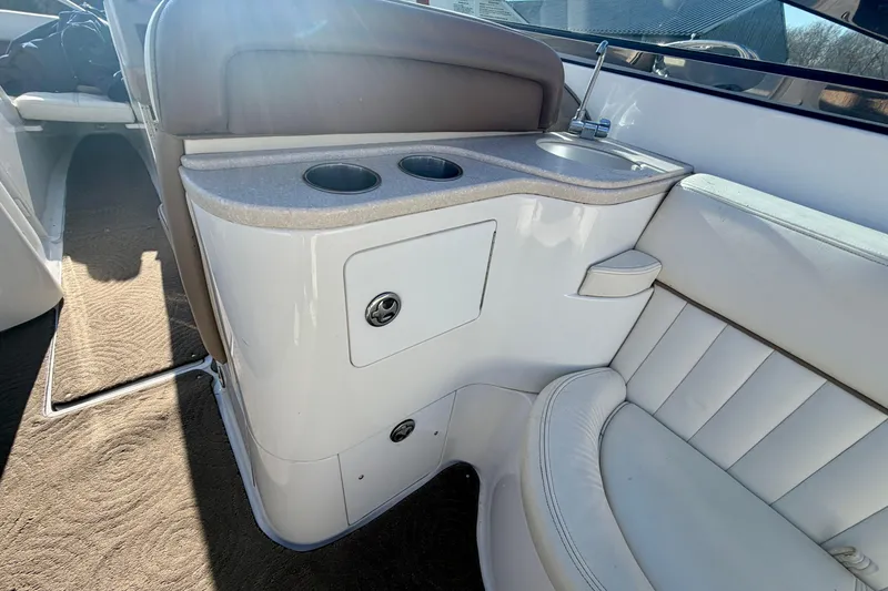 Slide: The Image of 2008 Cobalt 282 boat interior with white seating and cup holders, parked on sandy ground. - 22