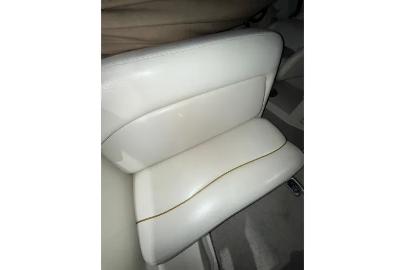 Slide: The Image of Interior seating of 2000 Sea Ray 240 Sundancer boat, featuring white upholstery and speaker. - 25