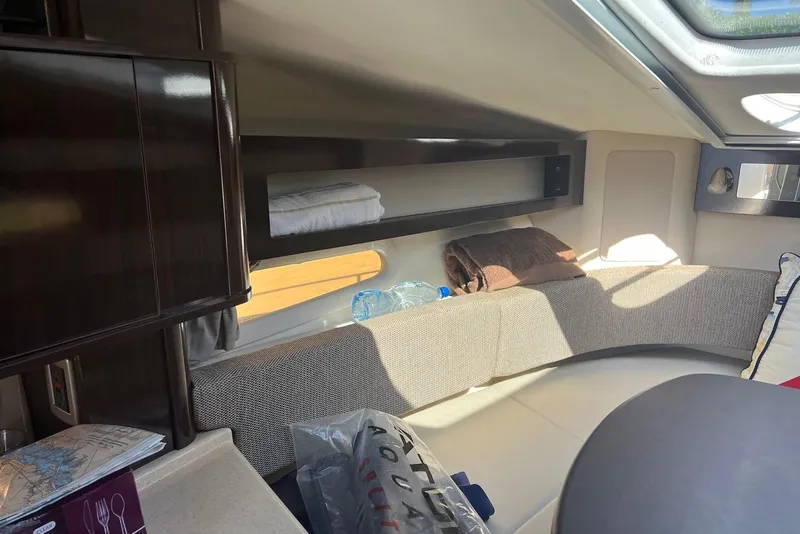 Slide: The Image of 2018 Sea Ray Sundancer 280 cabin interior with seating, storage, and natural light. - 24