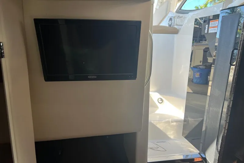 Slide: The Image of Interior view of 2018 Sea Ray Sundancer 280 with mounted TV and open cabin door. - 27