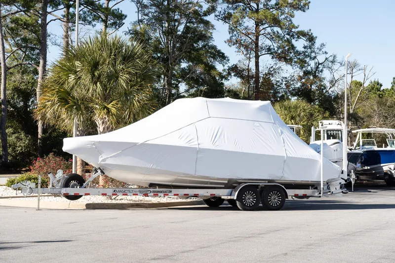 The Image of Covered 2026 Solace 28 HCS boat on trailer, parked outdoors with trees in background. - 0