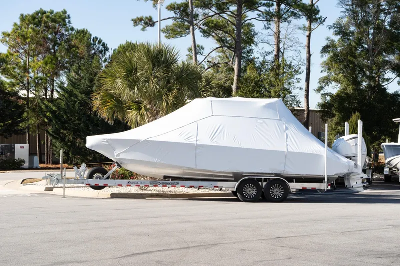 Slide: The Image of 2026 Solace 28 HCS boat covered on trailer, parked outdoors near trees. - 1