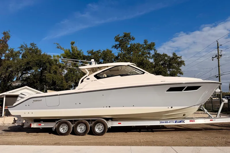 The Image of 2018 Pursuit DC 365 Dual Console boat on trailer, parked outdoors. - 0