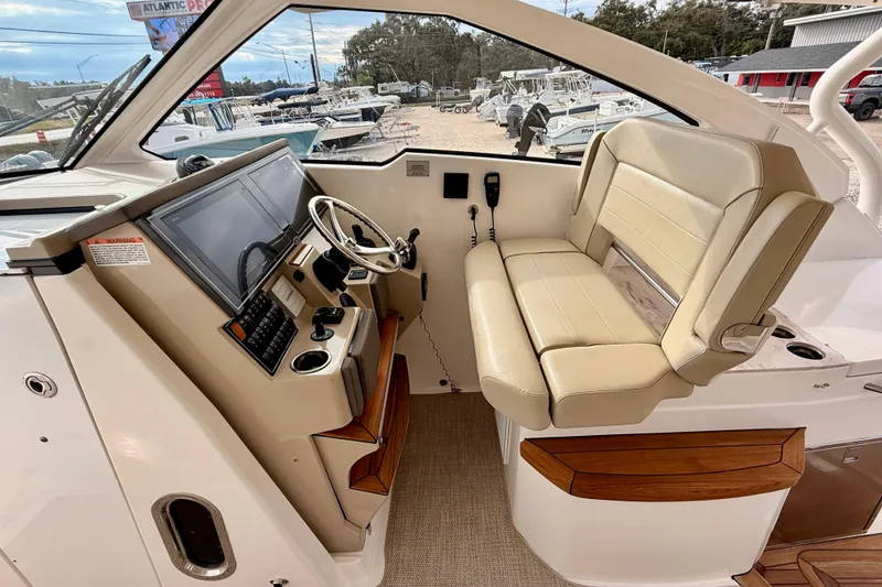 Slide: The Image of 2018 Pursuit DC 365 Dual Console boat interior with helm, steering wheel, and beige seating. - 13