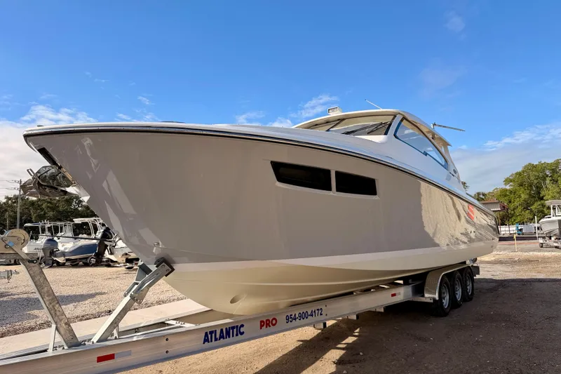 Slide: The Image of 2018 Pursuit DC 365 Dual Console boat on trailer under clear blue sky. - 2