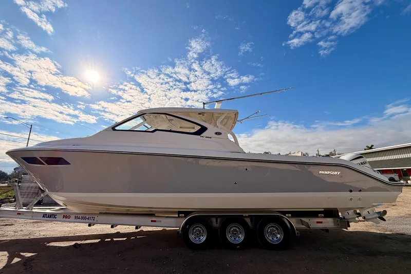 Slide: The Image of 2018 Pursuit DC 365 Dual Console boat on trailer under a bright blue sky. - 3