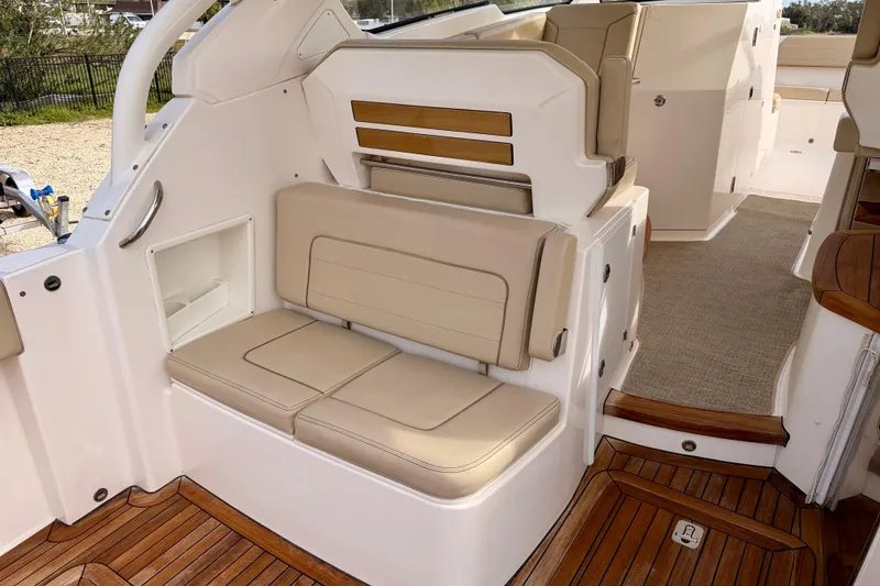 Slide: The Image of 2018 Pursuit DC 365 Dual Console boat interior with beige seating and wooden flooring. - 30