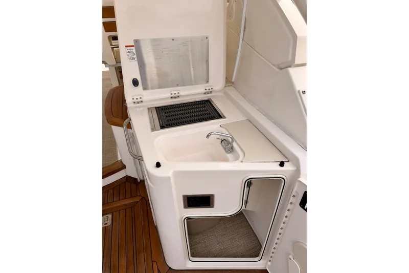 Slide: The Image of 2018 Pursuit DC 365 Dual Console boat interior with sink and storage area. - 32