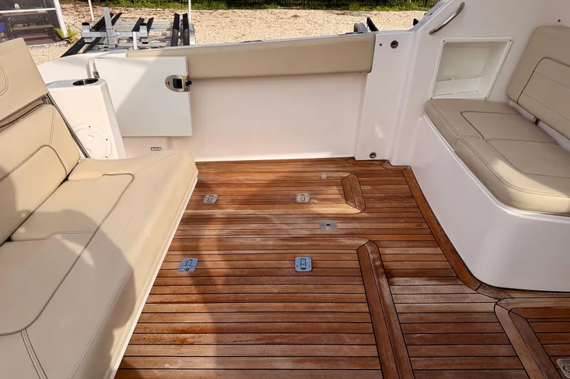 Slide: The Image of 2018 Pursuit DC 365 Dual Console boat interior with teak flooring and beige seating. - 35