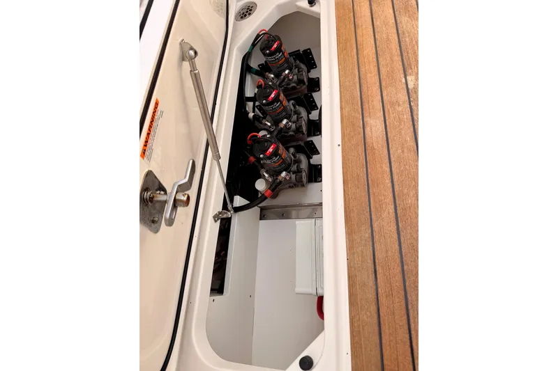 Slide: The Image of 2018 Pursuit DC 365 Dual Console boat storage compartment with equipment and wooden deck. - 57