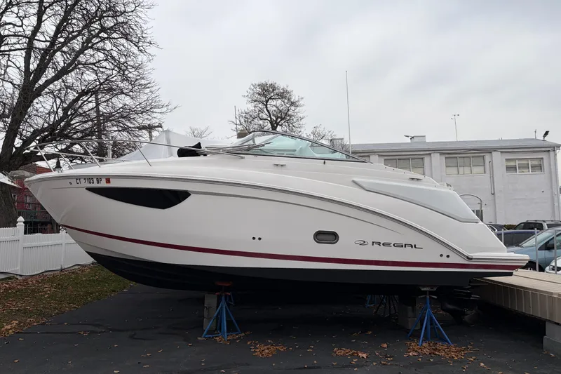The Image of 2016 Regal 2660 Express Cruiser boat on stands, parked outdoors. - 1