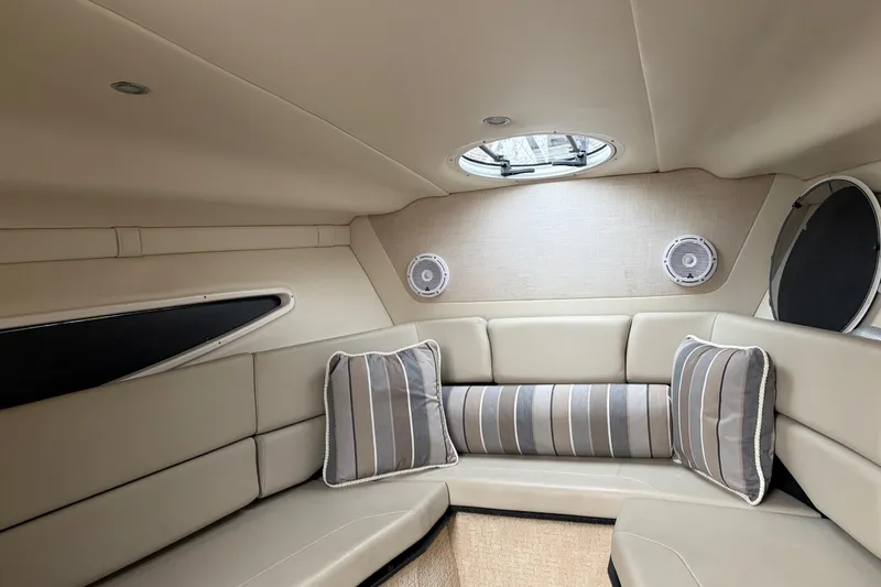 Slide: The Image of 2016 Regal 2660 Express Cruiser cabin with beige seating and striped cushions. - 5