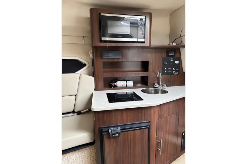 Slide: The Image of 2016 Regal 2660 Express Cruiser interior kitchen with microwave, sink, and stove. - 6