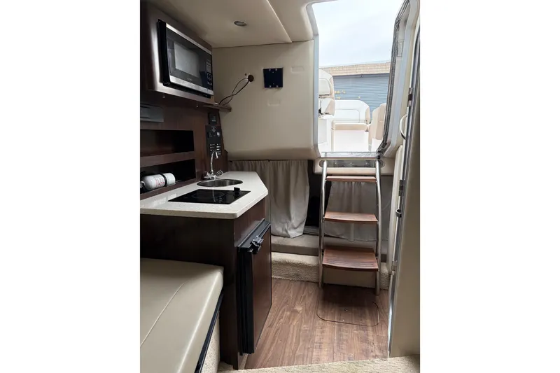 Slide: The Image of 2016 Regal 2660 Express Cruiser interior with kitchenette and wooden steps. - 7