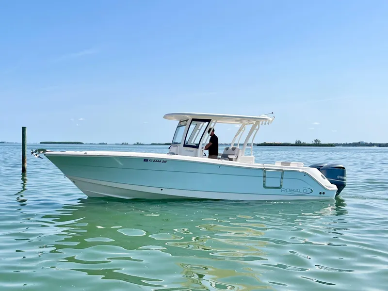 Slide: The Image of 2020 Robalo R302 Center Console boat on calm water under clear blue sky. - 1