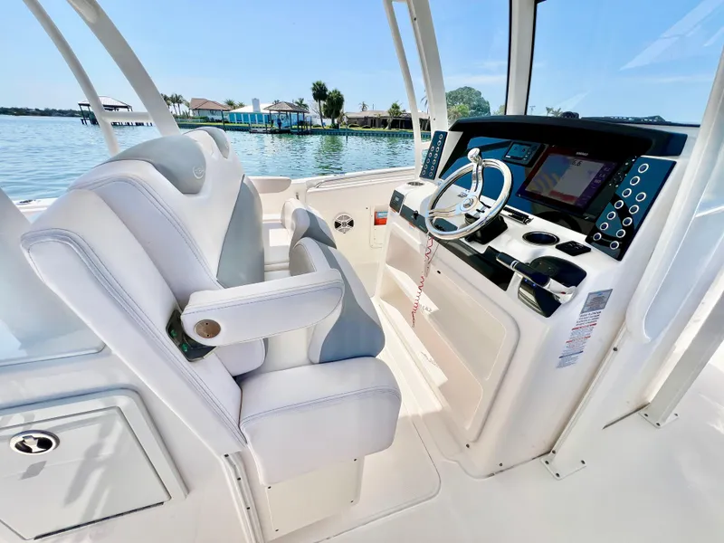 Slide: The Image of 2020 Robalo R302 Center Console boat interior with helm and seating, overlooking serene waters. - 15