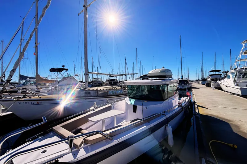 Slide: The Image of 2022 Axopar 28 AFT CABIN boat docked in sunny marina with sailboats. - 2