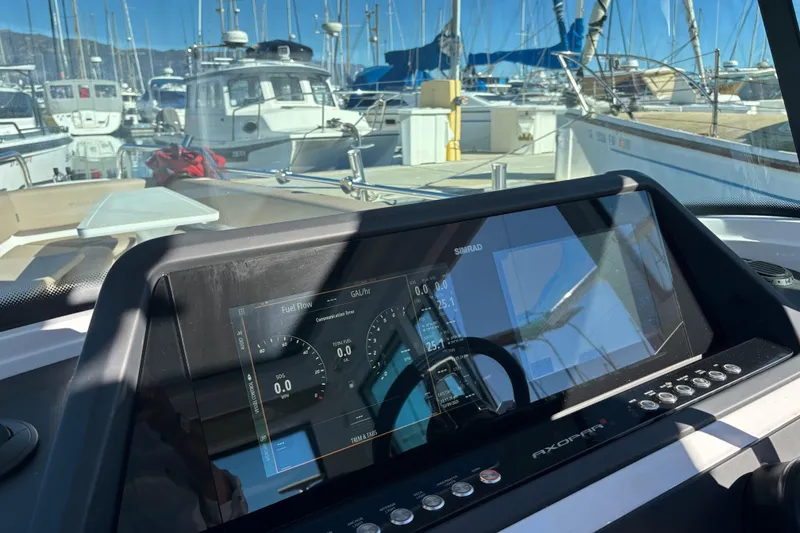 Slide: The Image of 2022 Axopar 28 AFT CABIN dashboard with Simrad display in marina setting. - 22