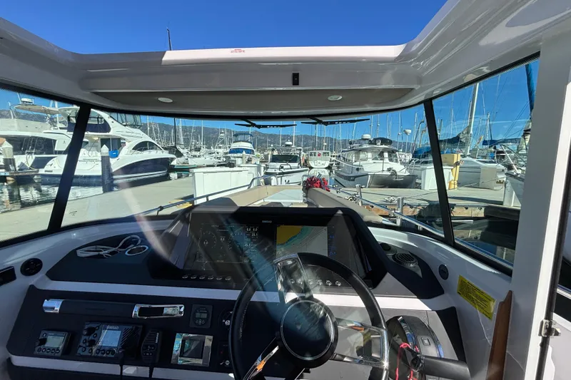 Slide: The Image of Interior view of 2022 Axopar 28 AFT CABIN boat at marina, showcasing dashboard and steering. - 23