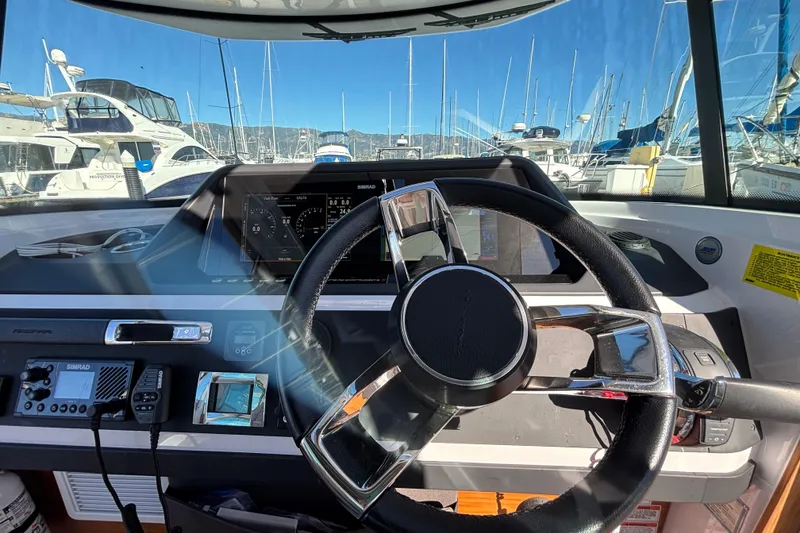 Slide: The Image of Interior view of 2022 Axopar 28 AFT CABIN boat cockpit with steering wheel and navigation controls. - 24