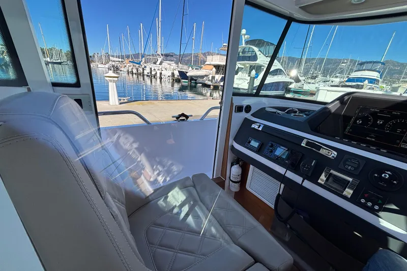 Slide: The Image of Interior view of 2022 Axopar 28 AFT CABIN, showcasing helm and marina backdrop. - 28