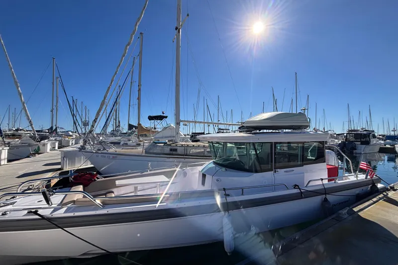 Slide: The Image of 2022 Axopar 28 AFT CABIN boat docked in a sunny marina with sailboats. - 3
